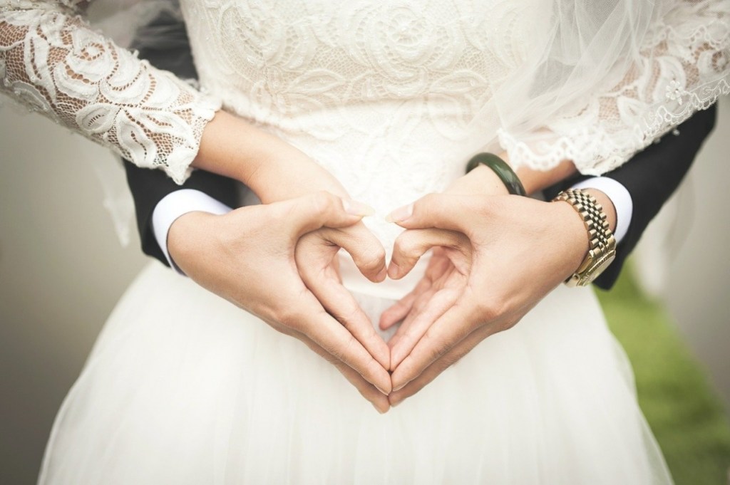 bride and groom making a heart symbol with their hands